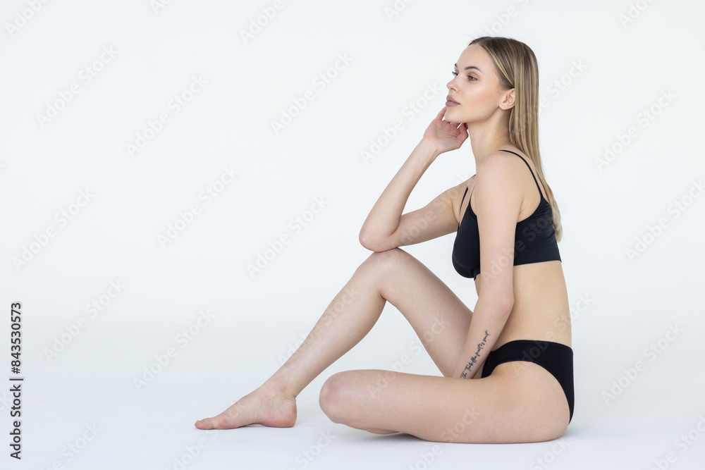 Young woman posing in black lingerie on white studio background with bare feet. Young woman posing in black lingerie on white studio background with bare feet.