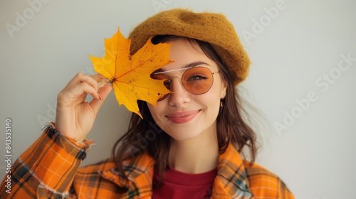 Young Woman Holding Autumn Leaf Against White Wall