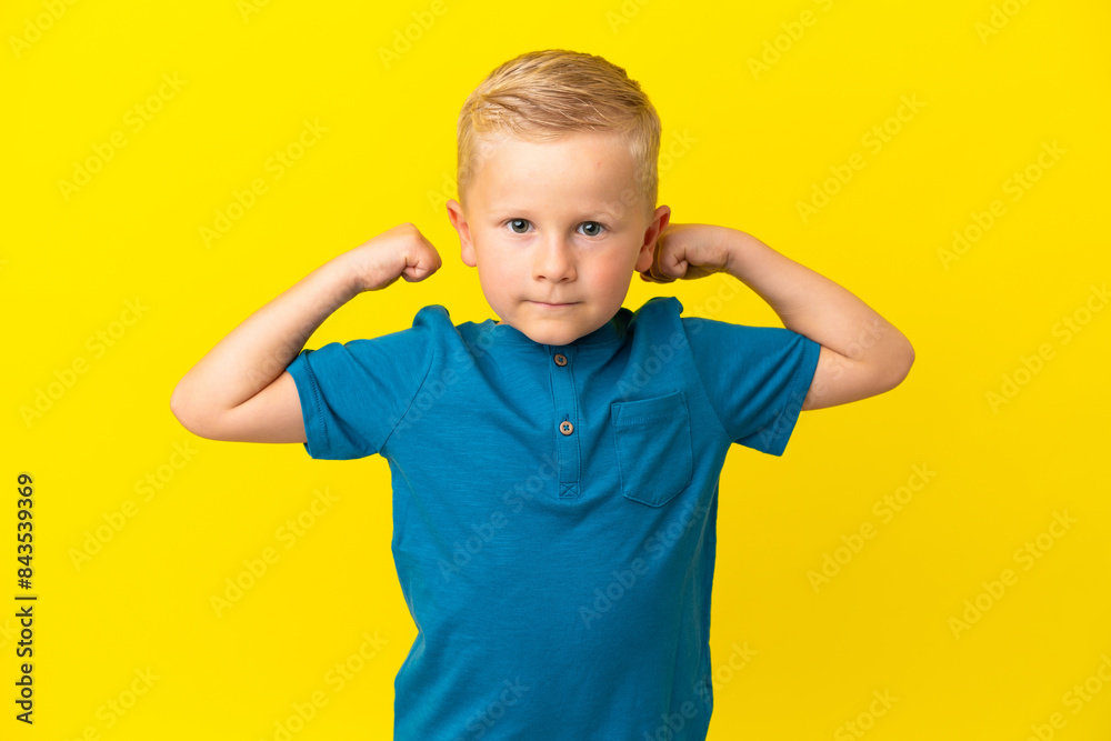 Little Russian boy isolated on yellow background doing strong gesture Little Russian boy isolated on yellow background doing strong gesture