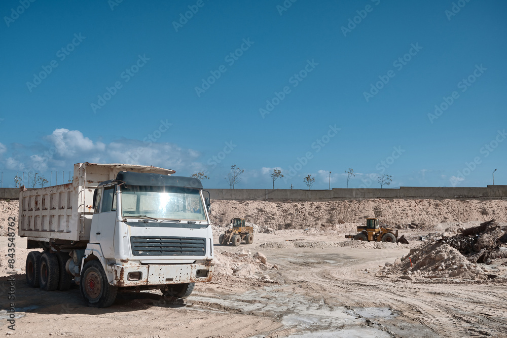 Two front loaders and tipper truck parked at limestone open pit mine. Earthmoving machnery. Dumper and loaders in a quarry