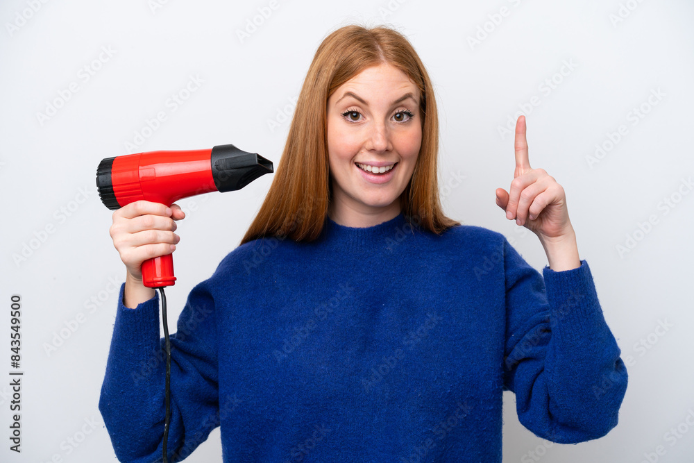 Young redhead woman holding a hairdryer isolated on white background pointing up a great idea Young redhead woman holding a hairdryer isolated on white background pointing up a great idea