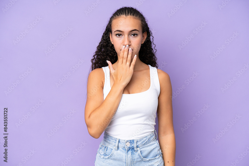 Young woman isolated on purple background covering mouth with hand Young woman isolated on purple background covering mouth with hand