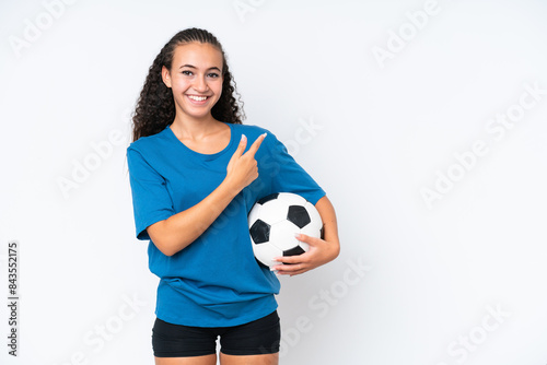 Young woman isolated on white background with soccer ball and pointing to the lateral