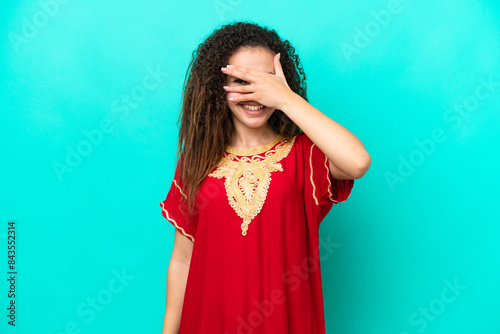 Young Arab woman isolated on blue background covering eyes by hands and smiling photo