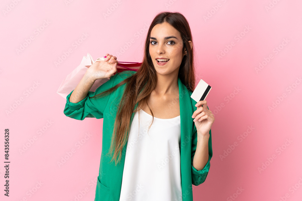 Young caucasian woman isolated on pink background holding shopping bags and a credit card Young caucasian woman isolated on pink background holding shopping bags and a credit card
