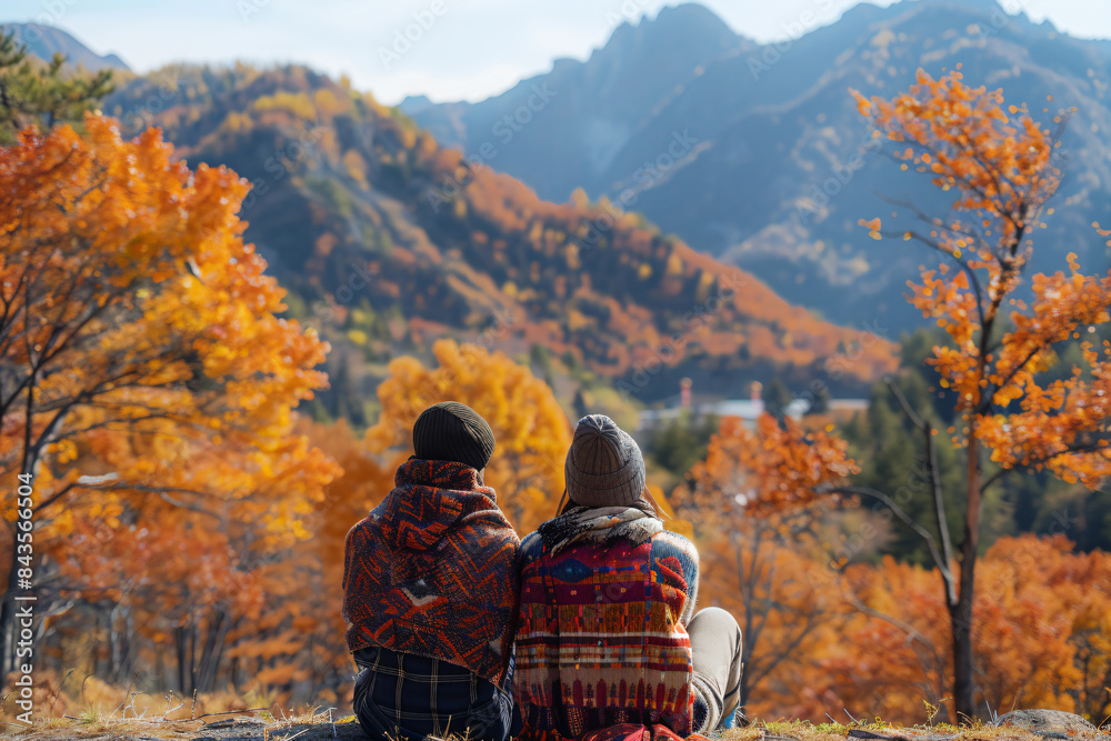two people sitting on a rock looking at the mountains two people sitting on a rock looking at the mountains