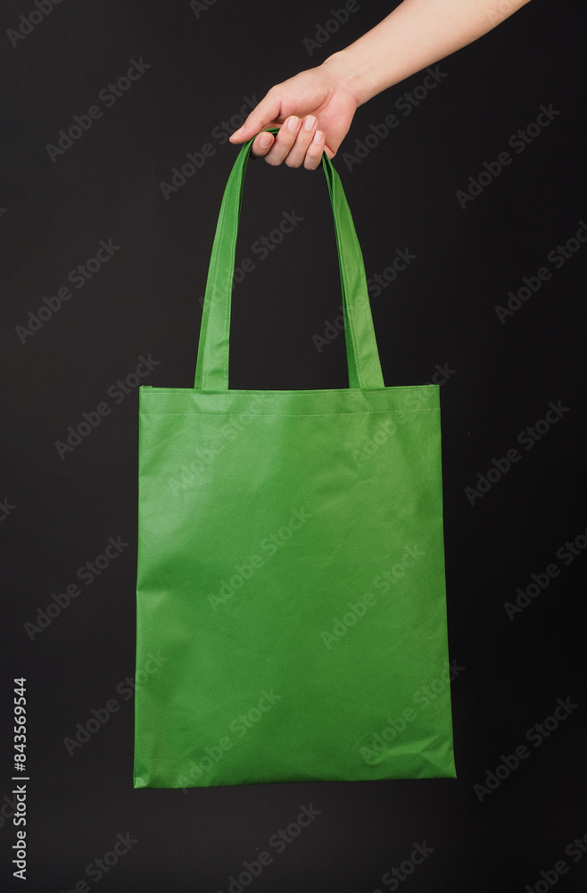 Hand is hold green Spunbond bag on black background. Hand is hold green Spunbond bag on black background.