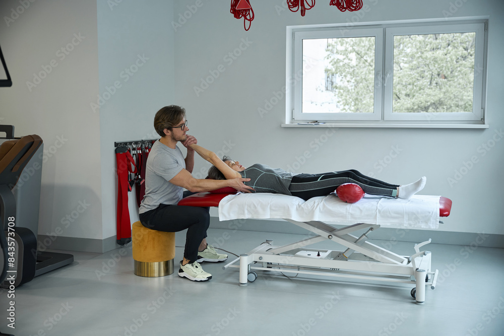 Fototapeta premium Rehabilitologist works with the shoulder joint of an elderly lady