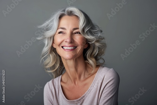 Smiling middle aged woman on grey background, single mature senior, studio portrait, Generative AI