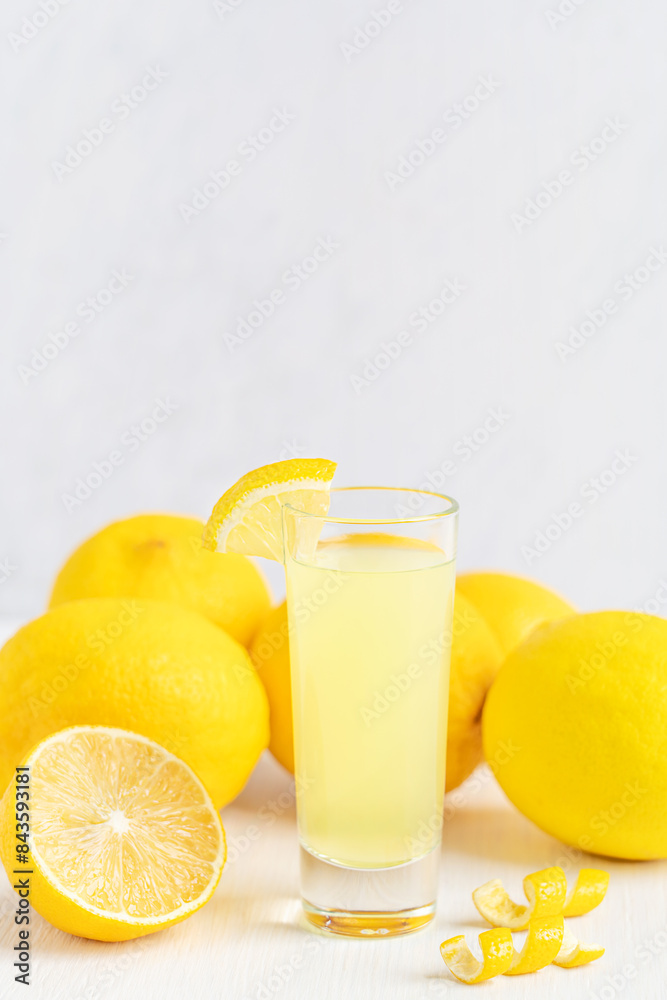 Limoncello Italian homemade sweet liqueur made from the zest of lemons served chilled as an digestif or aperitif in glass shot on white wooden table with citrus fruit ingredients with copy space Limoncello Italian homemade sweet liqueur made from the zest of lemons served chilled as an digestif or aperitif in glass shot on white wooden table with citrus fruit ingredients with copy space