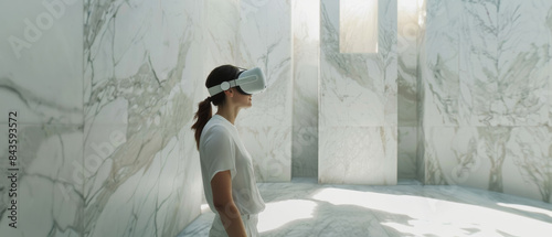 A woman immersed in virtual reality, wearing VR goggles in a spacious, bright marble room, merging futuristic technology with timeless elegance.