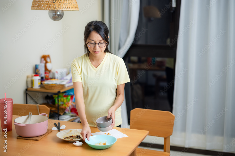 Pregnant woman clean up the dishes after the dinner at home Pregnant woman clean up the dishes after the dinner at home