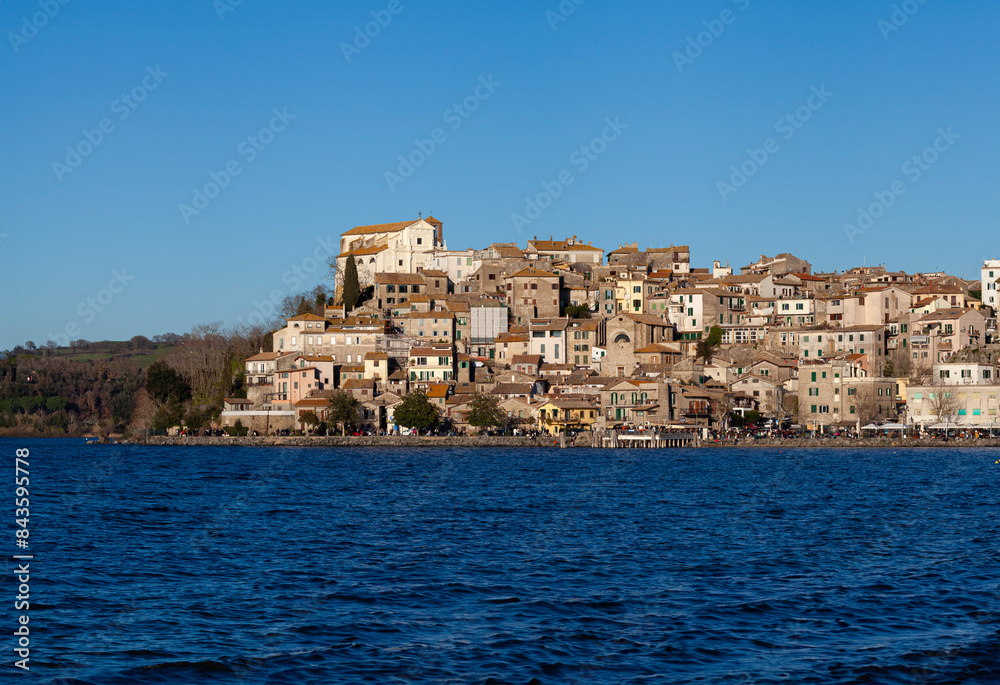 Picturesque view of Anguillara Sabazia from Lake Bracciano beach (Anguillara Sabazia is located in the province of Metropolitan City of Rome Capital) Picturesque view of Anguillara Sabazia from Lake Bracciano beach (Anguillara Sabazia is located in the province of Metropolitan City of Rome Capital)