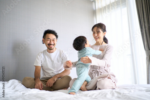 ベッドではしゃぐ3人家族 © folyphoto