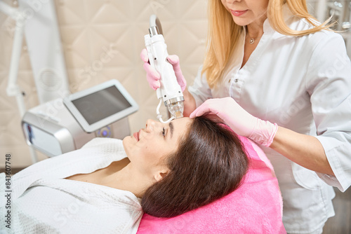 Bild auf Leinwand Client undergoing radio frequency microneedling treatment by cosmetologist