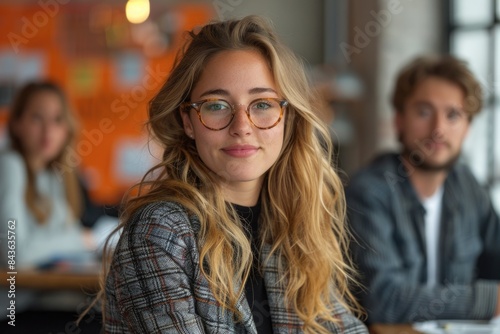 A smiling young woman with glasses in a professional setting, conveying confidence and approachability