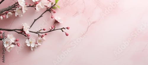 A flower arrangement featuring spring branches of a blooming apple tree on a pastel pink marble background There s a blank paper and ample copy space in the image Top view