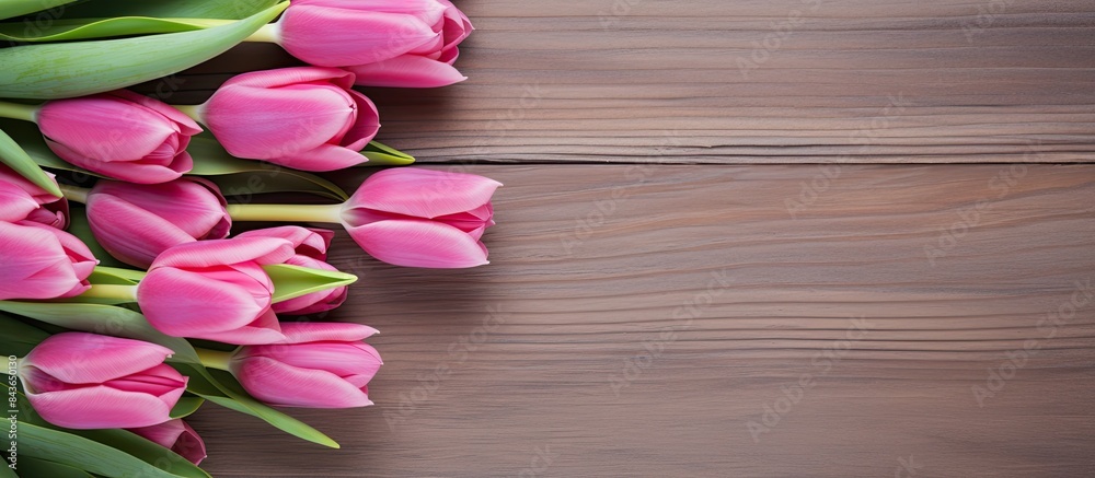 A lovely arrangement of pink tulips in a vase positioned on a natural wooden backdrop with the text hello spring on paper nearby Copy space image for text Celebrating the arrival of spring A lovely arrangement of pink tulips in a vase positioned on a natural wooden backdrop with the text hello spring on paper nearby Copy space image for text Celebrating the arrival of spring