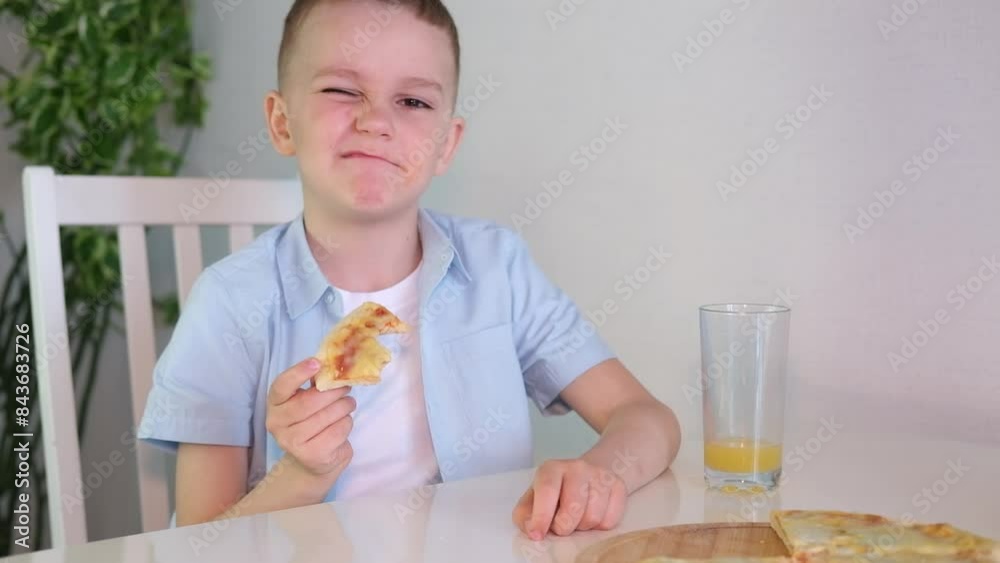 Cute little boy drinks glass of orange juice while having breakfast at home in kitchen. Cute little boy drinks glass of orange juice while having breakfast at home in kitchen.