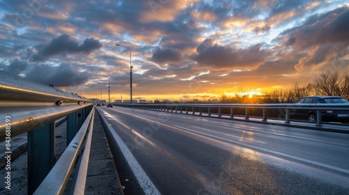 Traffic on the highway at sunset Roads with metal or rail safety barriers Cars on the asphalt under a cloudy sky