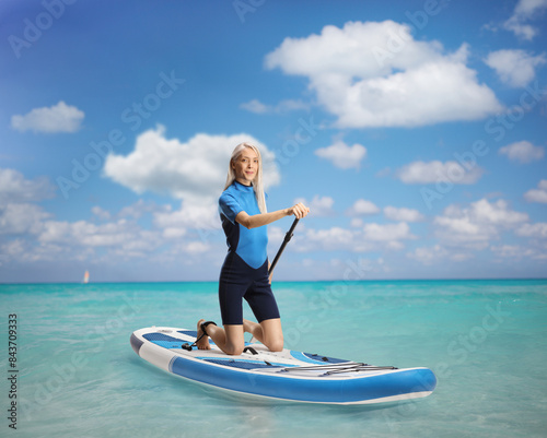 Woman in a wetsuit with a paddle kneeling on a sup © Ljupco Smokovski