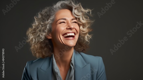 a mid-aged businesswoman laughing heartily, her genuine joy radiating through her warm smile.