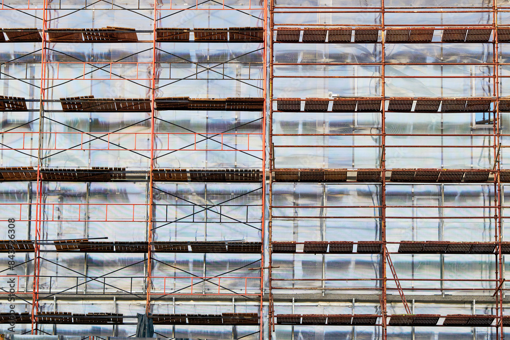 Building in scaffolding, construction of modern residential building, finishing facade works. Building in scaffolding, construction of modern residential building, finishing facade works.