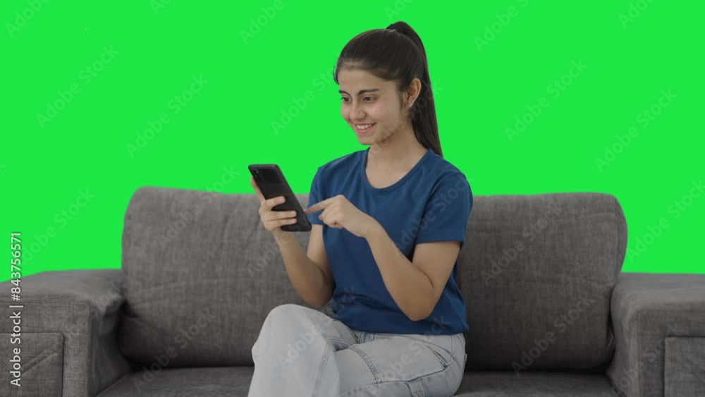 Happy Indian teenage girl scrolling through phone Green screen Happy Indian teenage girl scrolling through phone Green screen