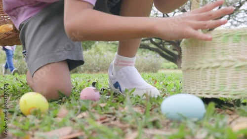 Group of children running to pick up colorful egg on easter egg hunt game in garden.