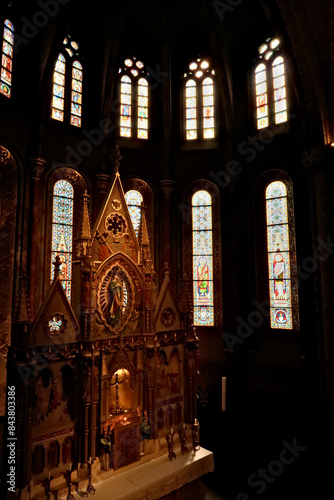 Elaborate altar in front of colorful stained glass windows in gothic style shape inside the Matthias Church  Budapest  Hungary