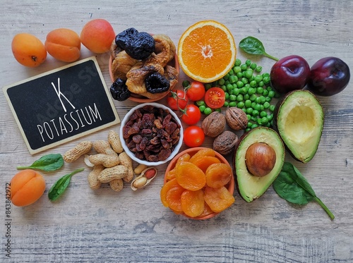 Potassium rich foods. High potassium foods with chemical symbol K. Natural dietary sources of potassium include dried apricot, orange, prunes, spinach, nuts, peanuts, raisins, peas, avocado, tomatoes. photo