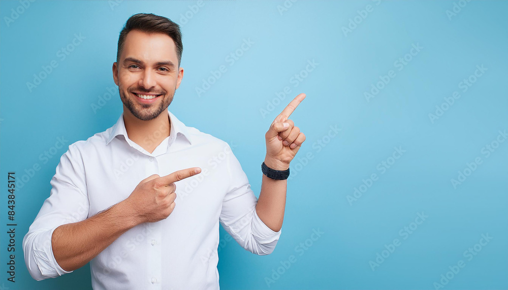 Man holds finger pointed on empty copy space background. Happy adult person pointing away at blue copy space for advertisement.