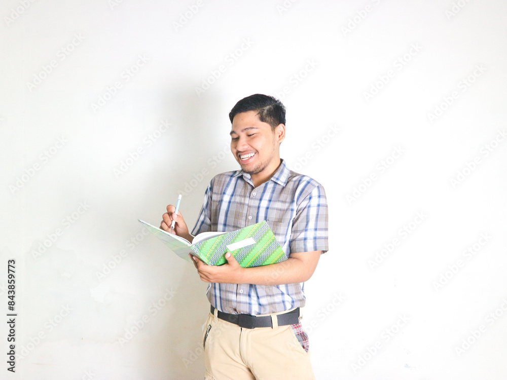 Cheerful young business man in plaid shirt posing isolated on white background. Achievement career wealth business concept. Mock up copy space. Hold hard cover book document write notes Cheerful young business man in plaid shirt posing isolated on white background. Achievement career wealth business concept. Mock up copy space. Hold hard cover book document write notes