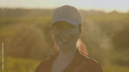 Portrait of a woman farmer against background of a yellow rapeseed field. pretty happy young woman standing in golden field. Fresh harvest. photo
