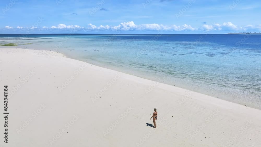 Aerial view of walking beautiful young woman on the sandbank in ocean, white sandy beach, blue sea, low tide at sunny summer day in Nakupenda, Zanzibar island. Top view of girl, sand spit, water, sky