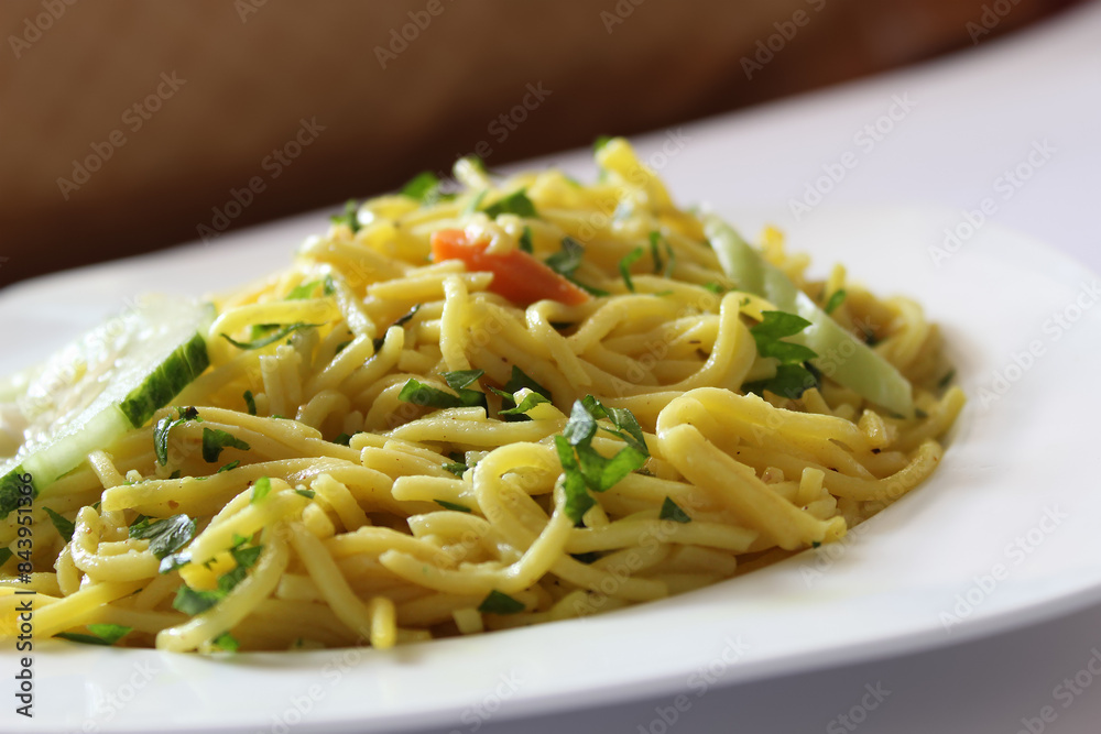 Close up shot of bami goreng garnished with celery and sliced carrots, mie goreng on a white plate with selective focus. Indonesian fried noodles with bokeh background. Close up shot of bami goreng garnished with celery and sliced carrots, mie goreng on a white plate with selective focus. Indonesian fried noodles with bokeh background.