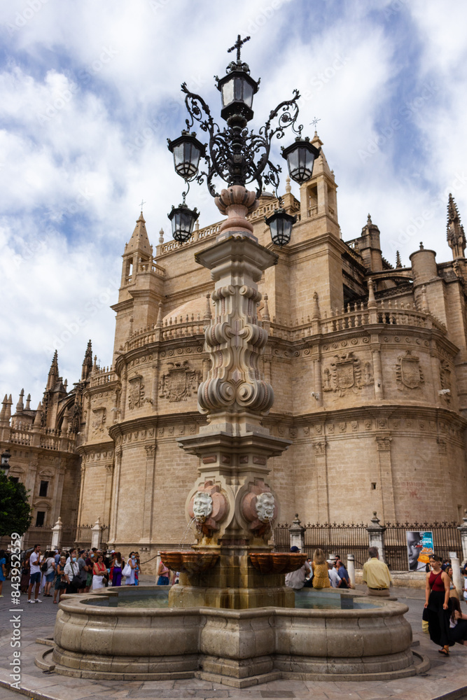 Seville, Spain, September 12, 2021: Farola Fountain and the Catedral de Sevilla (Cathedral of Saint Mary of the See).