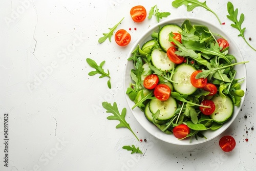 Fresh salad with cherry tomatoes, cucumber and arugula in a bowl on a white background. Top view. Space for text.