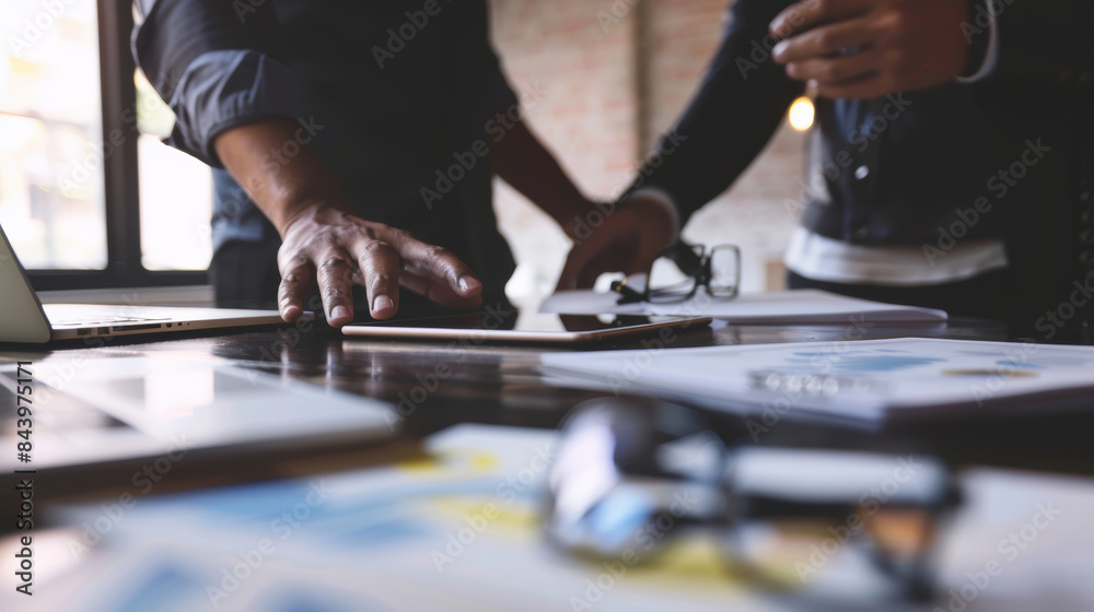 Two professionals collaborate at a desk, reviewing documents and engaging in a productive discussion in an office setting. Two professionals collaborate at a desk, reviewing documents and engaging in a productive discussion in an office setting.