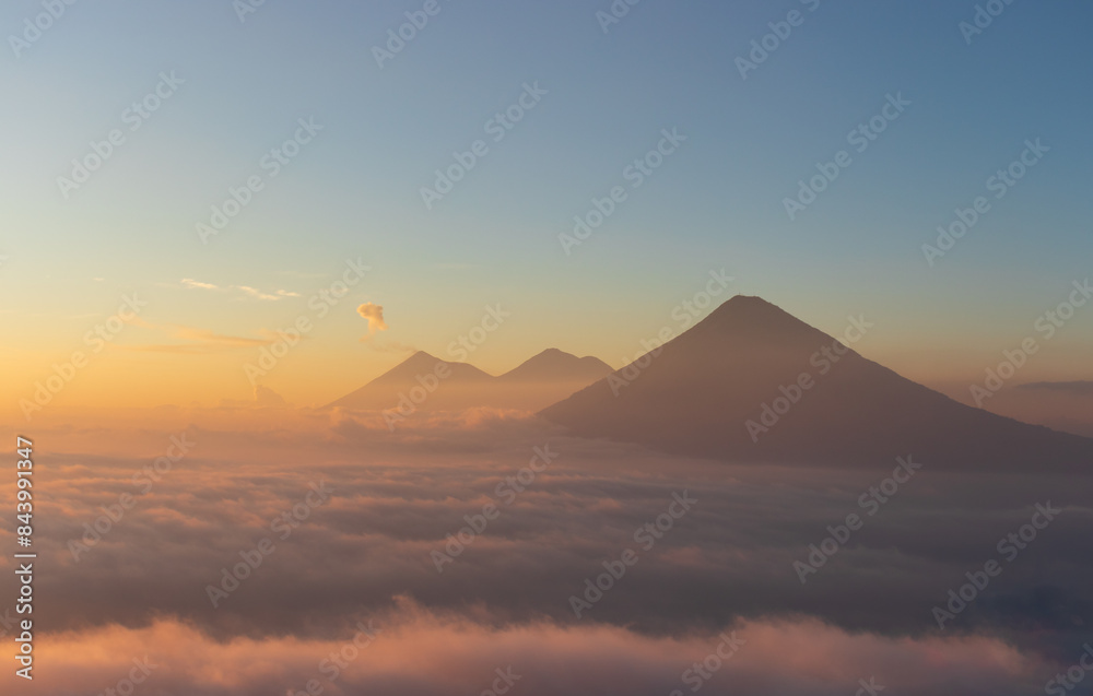 Volcanos agua acatenango and fuego in guatemala with colorful sunset above clouds