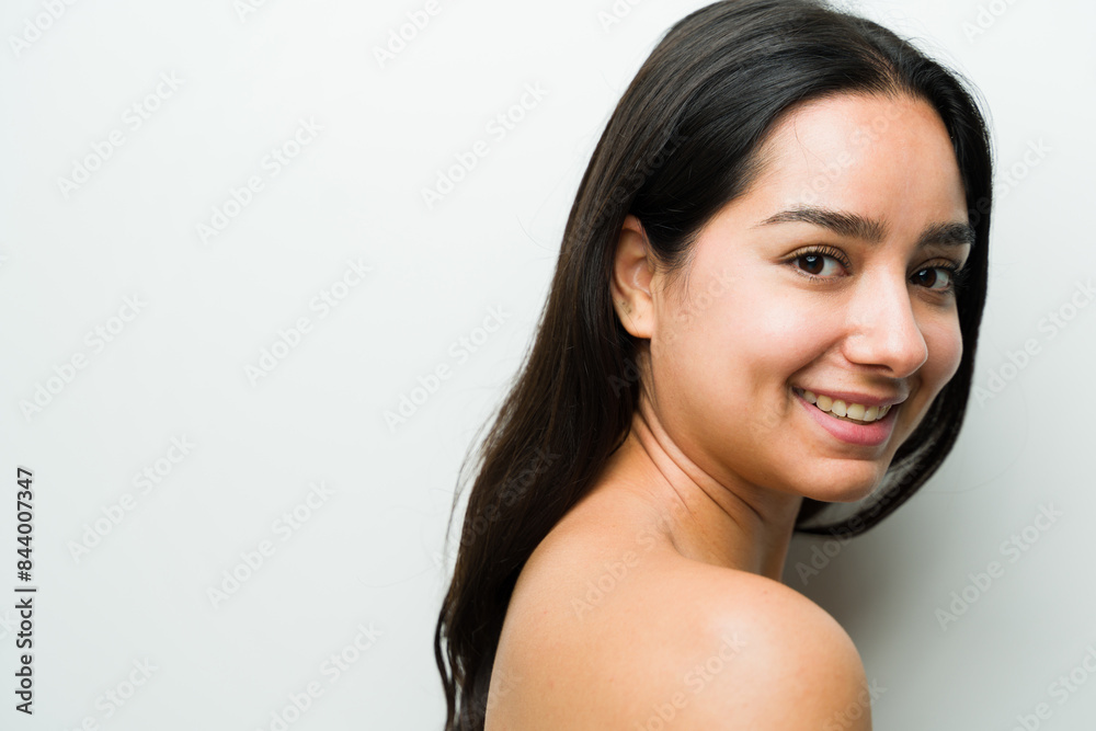 Gorgeous young latina woman flashes a gentle smile while showcasing her flawless skincare routine in a studio setting Gorgeous young latina woman flashes a gentle smile while showcasing her flawless skincare routine in a studio setting