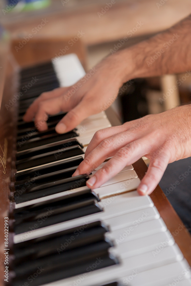 The hands of a man on the keys of a traditional piano learns to play the notes, the manlearns to play the piano online.