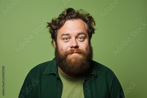 Portrait of a funny young man with a beard and mustache on a green background © Stocknterias