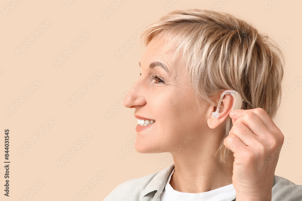 Mature woman with hearing aid on beige background Mature woman with hearing aid on beige background