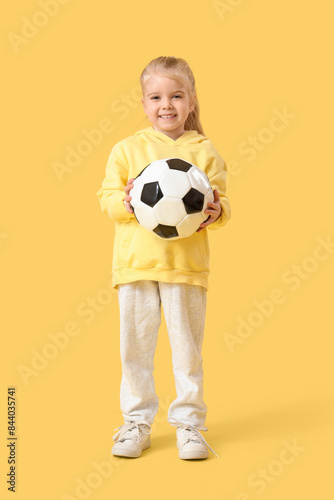 Cute little girl with soccer ball on yellow background © Pixel-Shot
