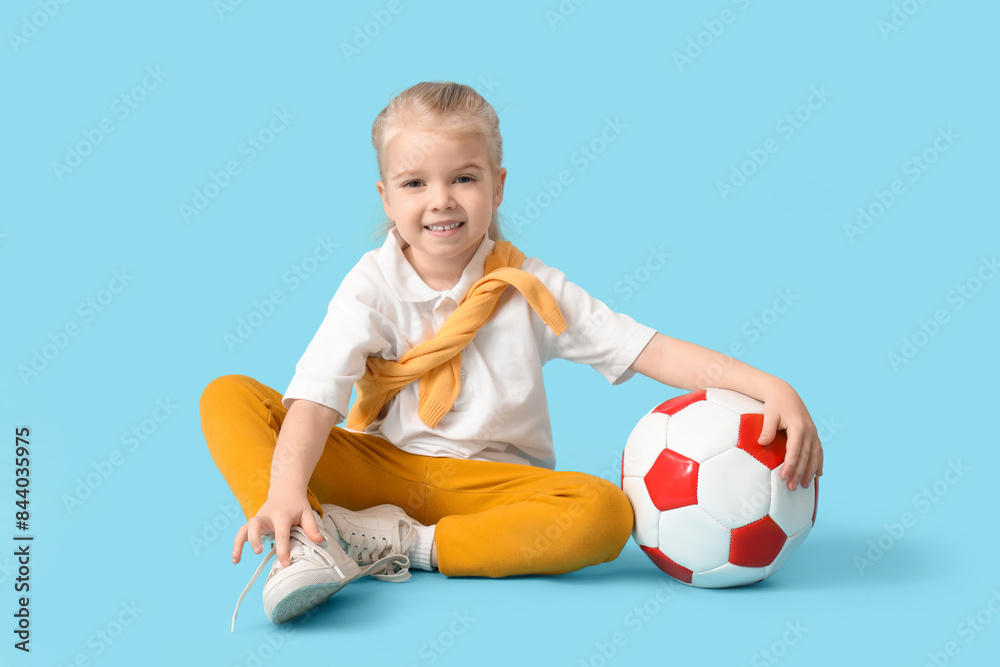 Cute little girl with soccer ball sitting on blue background Cute little girl with soccer ball sitting on blue background