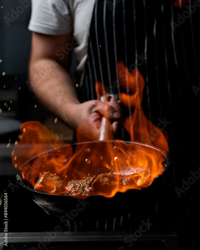 Wok pan cooking asian food with fire flames and flaming meat and vegetables. Hotel professional service food photo concept. Cooking recipe by chef menu.