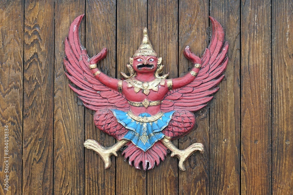 Obraz premium A vintage garuda statue on wooden fence background. 