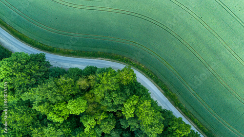 Aerial view landscape of winding road in the forest with a wheat field.