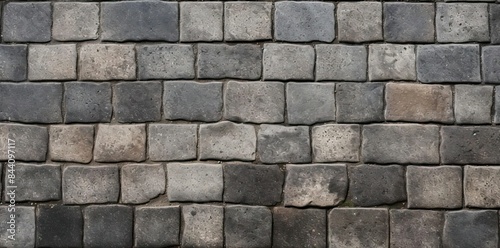 pavement texture seamless pattern of gray bricks and square stones, with a gray wall in the background